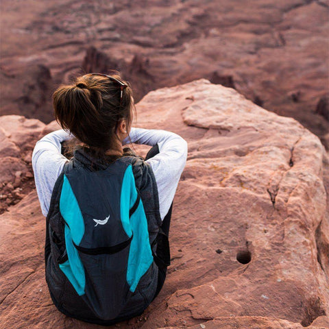 Adventurer with Trek Light Bindle Daypack at cliff's edge, enjoying the view and planning the next adventure.