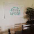 Trek Light's This Must Be The Place Canvas Flag hanging in a room, made from 10oz cotton canvas with hand-screened ink details.