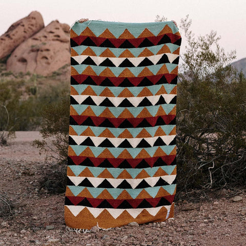 Beautiful handwoven Cascade Blanket made from recycled clothing materials, with vibrant patterns, cozy and versatile for any setting. By Trek Light.