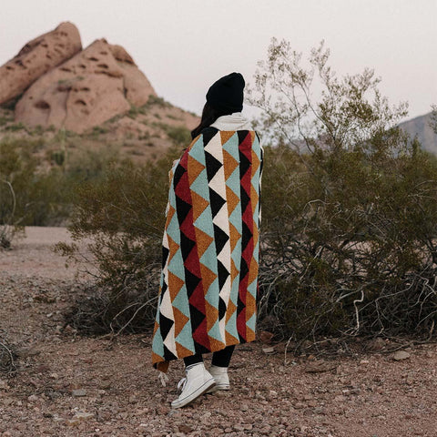 Beautiful handwoven Cascade Blanket made from recycled clothing materials, showcasing cozy and versatile design in a scenic landscape. By Trek Light.