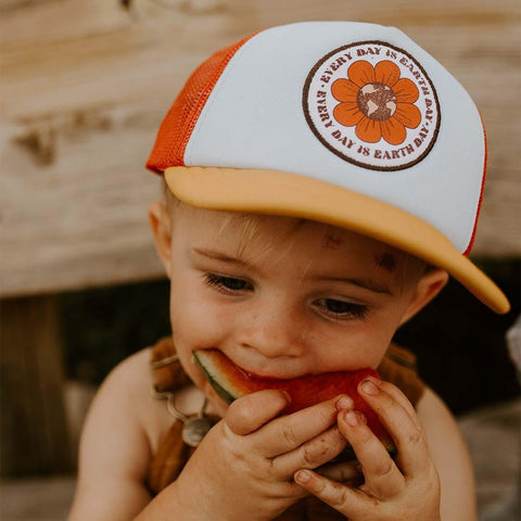 Alt Tag: Toddler wearing Trek Light Earth Day hat, enjoying watermelon outdoors. Eco-friendly 5-panel snapback for everyday adventures.