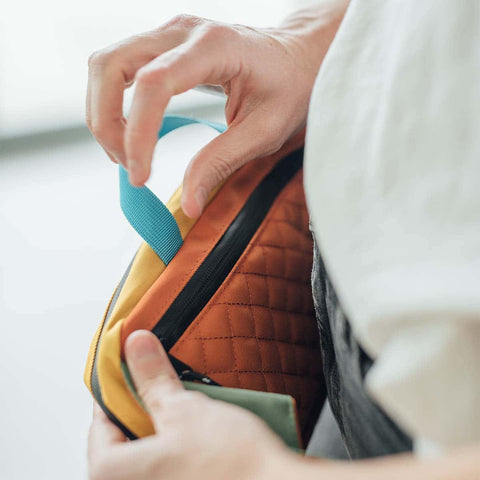 Person holding Trek Light Everyday Fanny Pack showcasing quilted design and zipper detail.