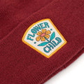 Trek Light Flower Child Kids Beanie in burgundy with floral patch detail, perfect for the young adventurers.