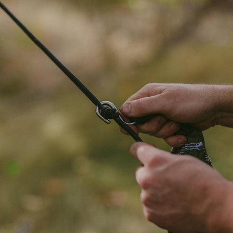 Hands setting up Trek Light's Go Anywhere Rope Kit, perfect for hammock adventures. Lightweight and ready to use right out of the pouch.