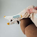 Cozy Trek Light Grateful Every Day socks, perfect stretch and comfort, worn by a relaxed person on a brown chair.