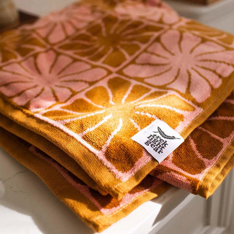 Close-up of folded Trek Light patterned towels with yellow and pink geometric design, perfect for cozying up in style.