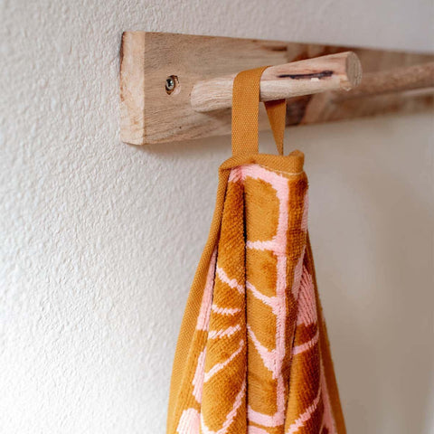 Orange and pink patterned towel hanging on a wooden rack, showcasing Trek Light home decor style.