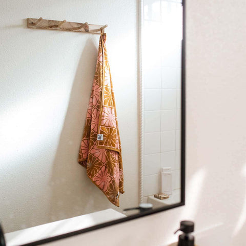 Trek Light towel with geometric pattern hanging in a bathroom, reflecting in a mirror. Cozy, stylish, and perfect for any bathroom setting.