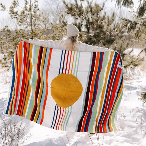 Person holding colorful Halley's Comet Blanket by Trek Light in snowy outdoors