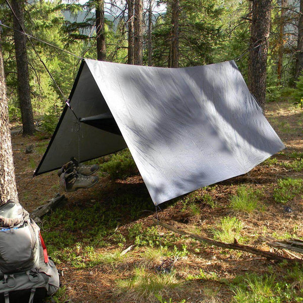 V9 Strong Tarp by Trek Light set up in the woods as a hammock rain fly, providing durable shelter for outdoor camping adventures.