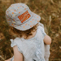 Child wearing a Happiest Camper kids hat with an all-over print design, perfect for adventures. Trek Light kids' hat outdoor fun.