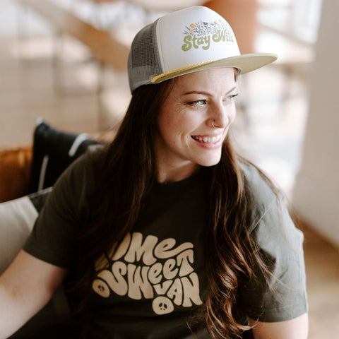 Woman smiling in Home Sweet Van shirt, army green, enjoying a cozy moment. Perfect Trek Light cotton comfort, handprinted in USA.