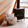 Cozy Huntington Blanket by Trek Light near a wood stove in a rustic cabin setting, perfect for beach or campfire nights.