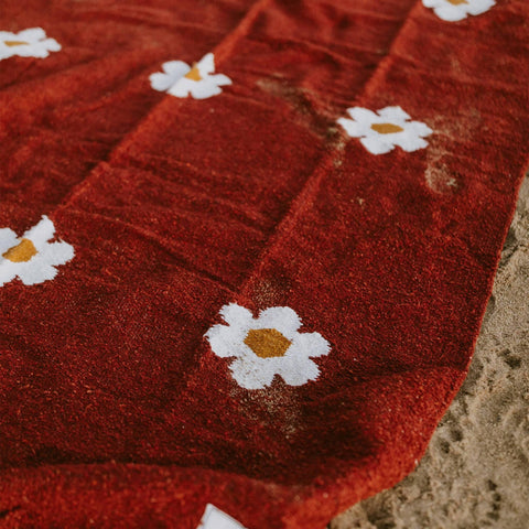 Lazy Daisy Blanket with charming daisy pattern on a red background, perfect for relaxing moments. Explore cozy with Trek Light.