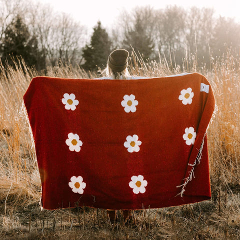 Trek Light Lazy Daisy Blanket in a serene field, featuring vibrant daisy designs for those relaxed, lazy moments in nature.