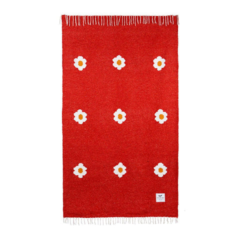 Red handwoven blanket with floral design from Trek Light, made from recycled materials.