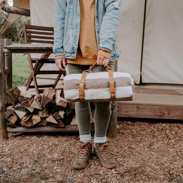 Person carrying a stylish Trek Light leather blanket carrier outdoors, showcasing its artisan craftsmanship.