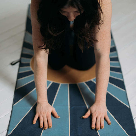 Person practicing yoga on a Trek Light mat, vibrant design radiating energy and calmness.