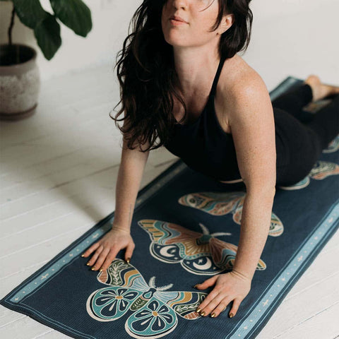 Woman practicing yoga on a colorful butterfly-patterned mat from Trek Light, enjoying a peaceful moment indoors.