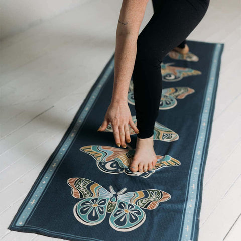 Person practicing yoga on a Painted Moth Yoga Towel made from recycled materials. Featuring Grip-Tex™ for stability by Trek Light Gear.