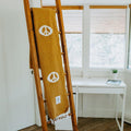 Cozy handwoven Peace Blanket from Trek Light on wooden ladder, made from recycled clothing materials.