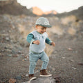 Toddler wearing a Peace Checkered Kids Hat with a Trek Light vibe, standing outdoors, feeling adventurous and cool in stylish denim and boots.