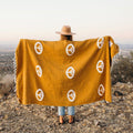 Person holding a beautiful handwoven Peace Blanket by Trek Light. made from recycled clothing materials, featuring peace symbols and vibrant yellow hue.