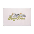 Trek Light Canvas Flag Wall Art with 'Stay Wild' print, featuring natural canvas, floral design, brass grommets, 31" x 48" size.