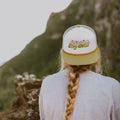 Back view of person wearing a Stay Wild foam trucker snapback hat in nature, perfect for outdoor adventures with Trek Light gear.