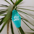 Retro Stay Wild key tag by Trek Light, hanging on a plant, perfect for vintage style lovers embracing the wild spirit.