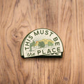 Trek Light desert sticker on wooden surface, featuring cactus design and text 'This Must Be The Place'. Made in the USA, weatherproof.