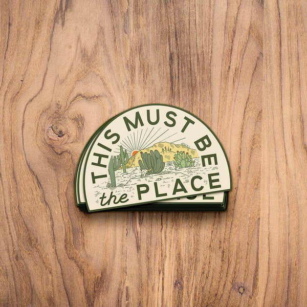 Trek Light desert sticker on wooden surface, featuring cactus design and text 'This Must Be The Place'. Made in the USA, weatherproof.