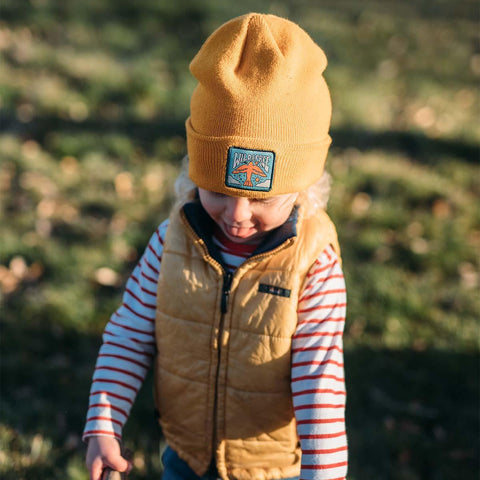 Toddler wearing Trek Light's Wild & Free Kids Beanie in a sunny park, showcasing playful outdoor style with adventure-ready vibes.