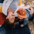 Child wearing a "You Are My Sunshine" hat by Trek Light while playing outdoors with a smiling adult.